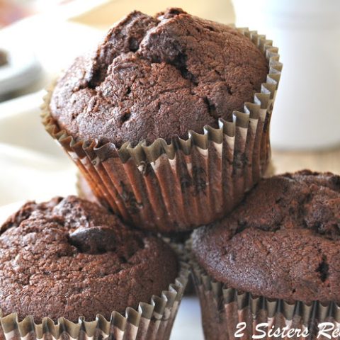 3 baked chocolate muffins on a white plate.