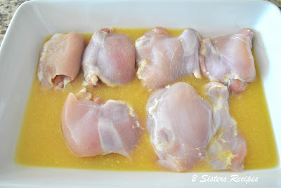 Raw chicken thighs marinating in a baking dish. by 2sistersrecipes.com