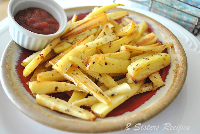 A platter with parsnip fries and a cup with ketchup on the side. by 2sistersrecipes.com