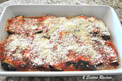 A white baking dish filled with eggplant rollatini. by 2sistersrecipes.com 