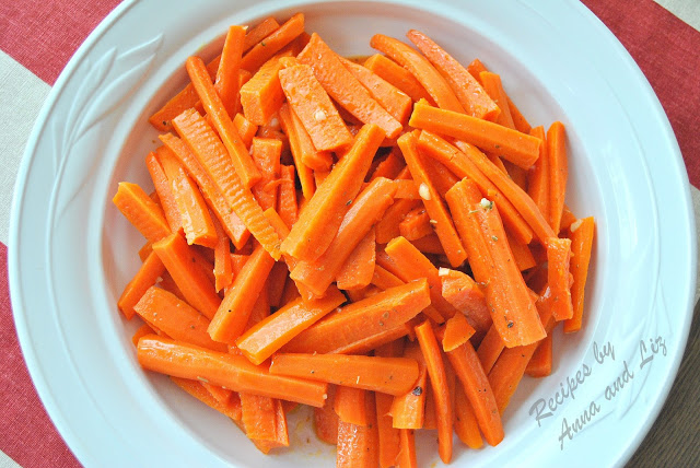 A round white ceramic bowl filled with cooked carrots sticks.