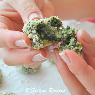 A hand holding a spinach ball and broke it apart. by 2sistersrecipes.com