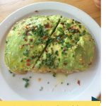 An avocado toast served on a white plate.
