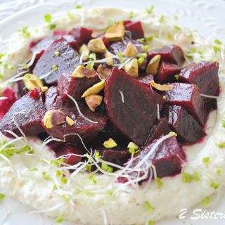 A beet salad served over a bed of creamy ricotta topped with chopped pistachios.