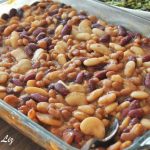 A mixture of baked beans in a sauce served in a glass baking dish.
