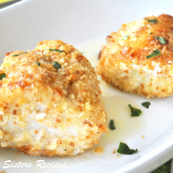 Two pieces of baked fish coated with bread crumbs served on a white plate.