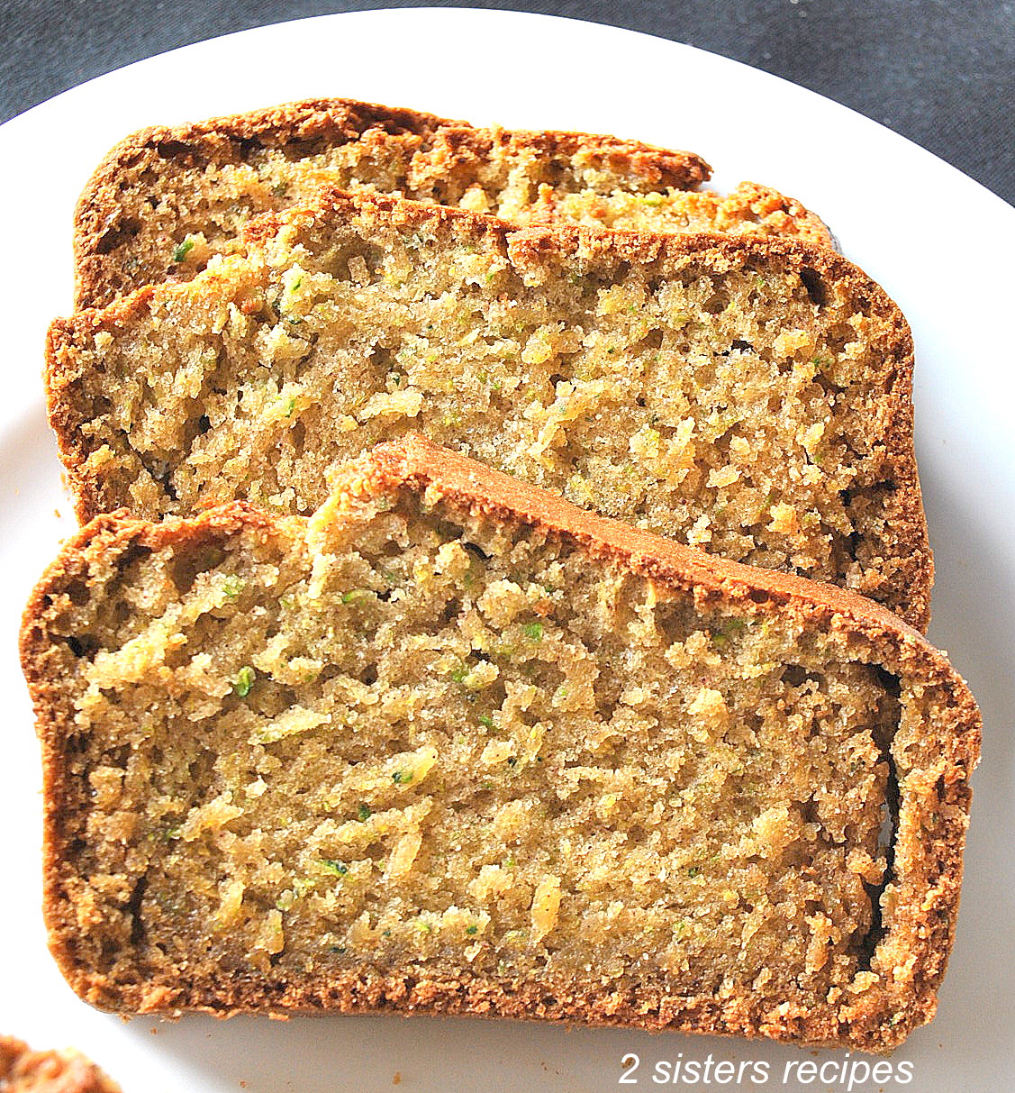 2 Slices of zucchini bread served on a white plate.