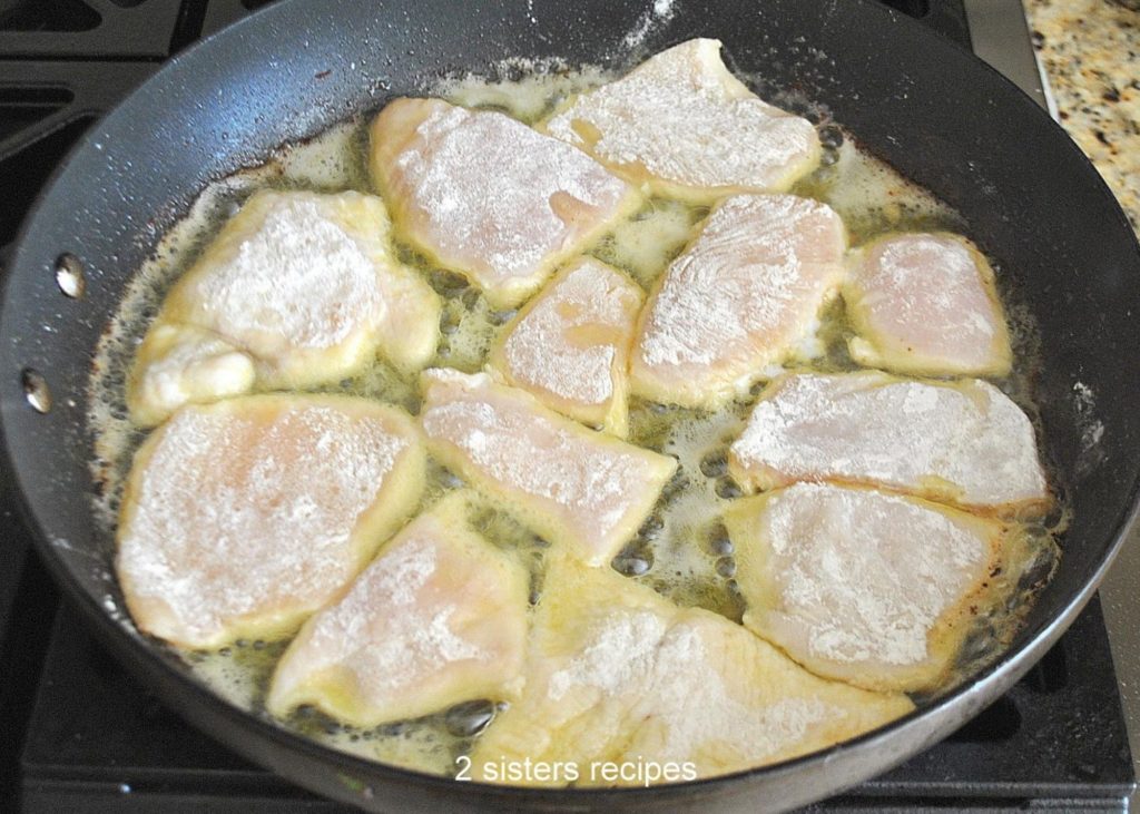 Floured pieces of chicken cutlets sauteing in a skillet.  by 2sistersrecipes.com