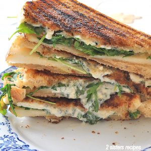 Grilled Cheese and Pear Sandwich piled on top of each other on a white and blue plate.