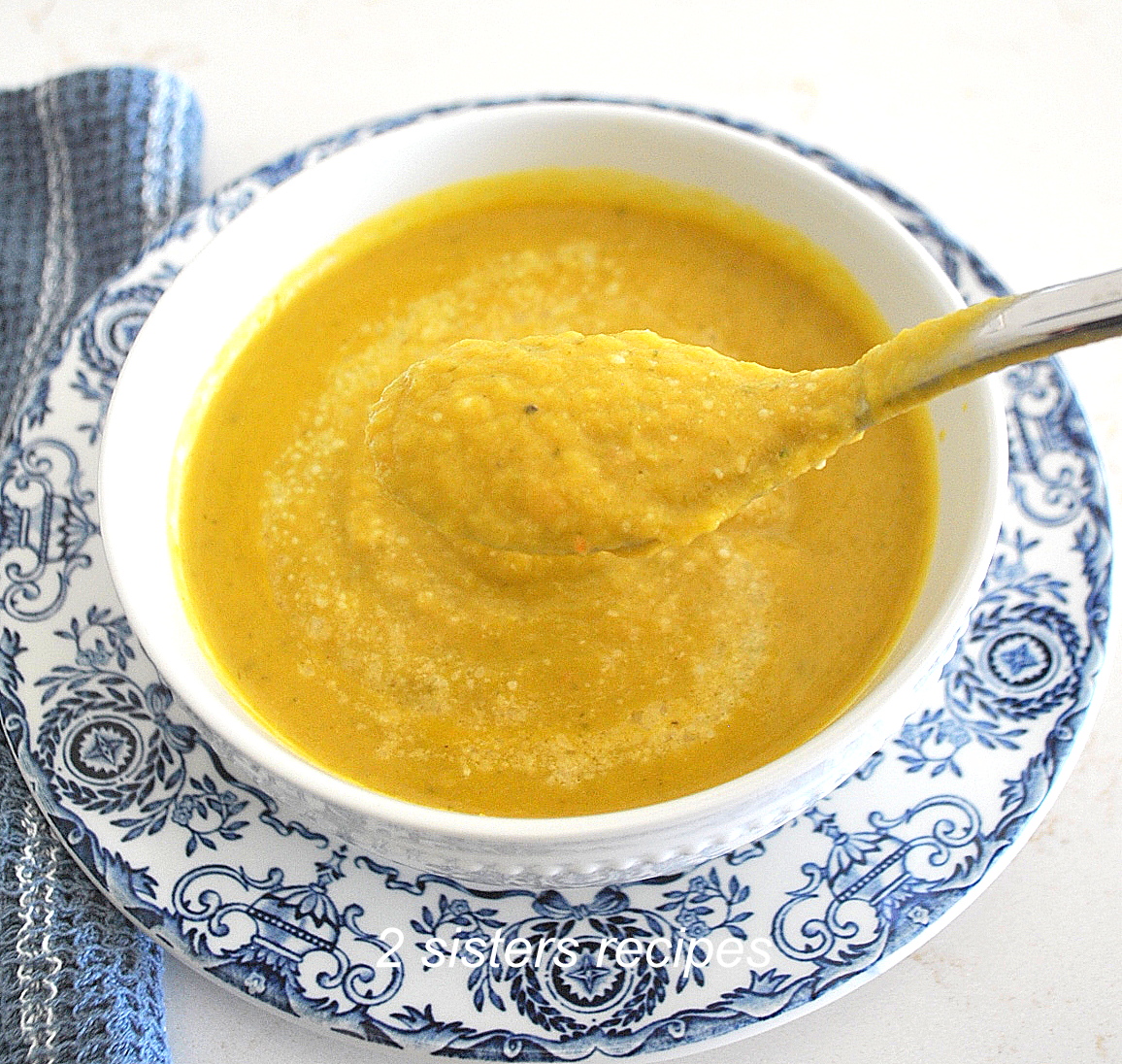 A spoonful of pureed soup over a white bowl filled with creamy brussels spouts soup.