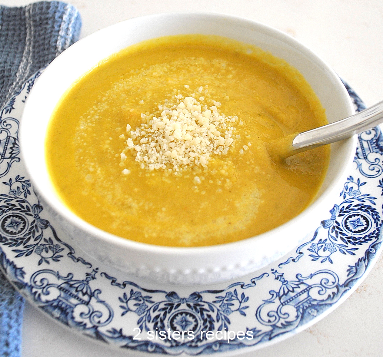 A white bowl filled with pureed brussels sprout soup, topped with some grated cheese.