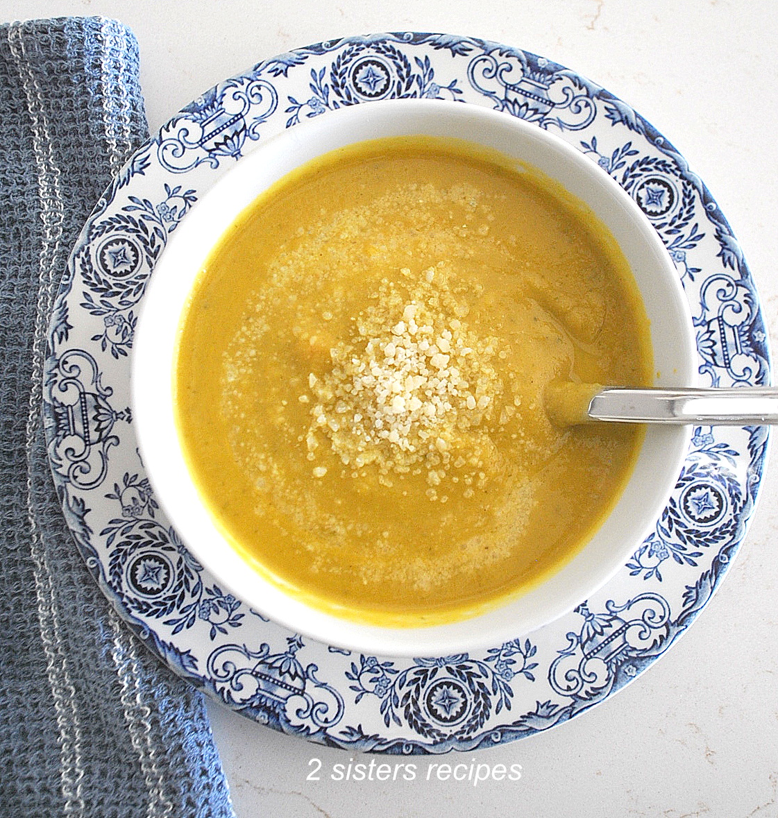 A white bowl filled with pureed brussels sprout soup, topped with some grated cheese.