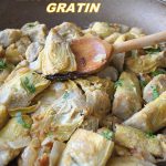 A large skillet filled with cooked artichoke hearts topped with parsley and bread crumbs.