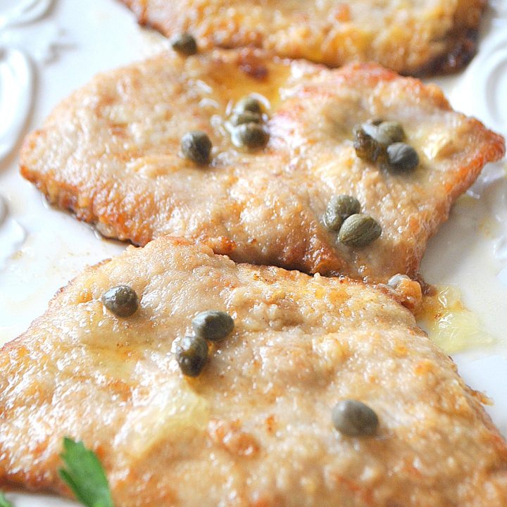 Three pieces of cooked veal with capers on top.
