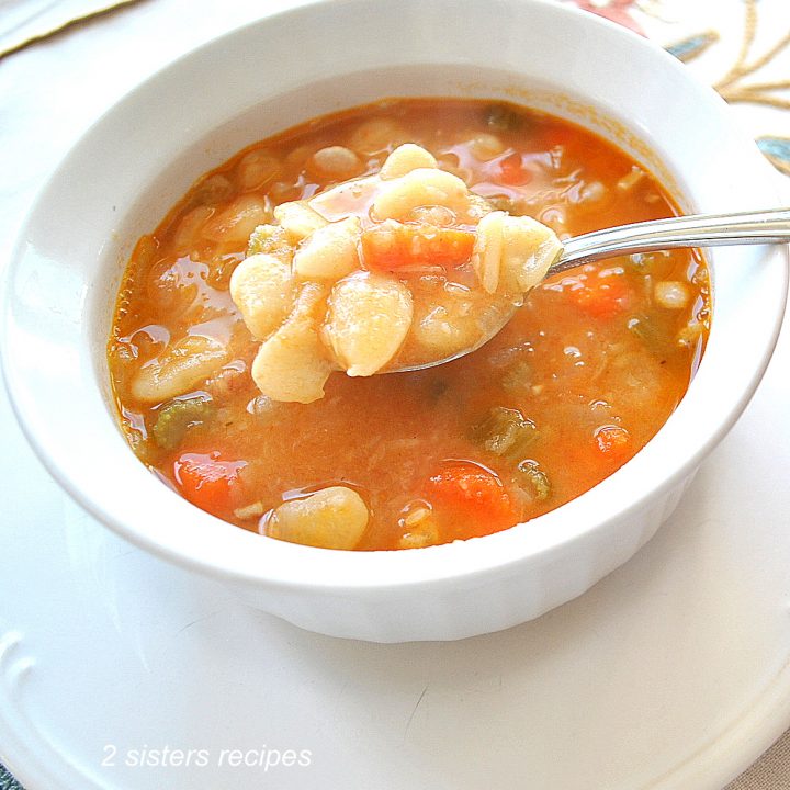 A white bowl filled with baby lima beans and vegetables soup.