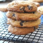A pile of chocolate chip cookies on a wire rack.