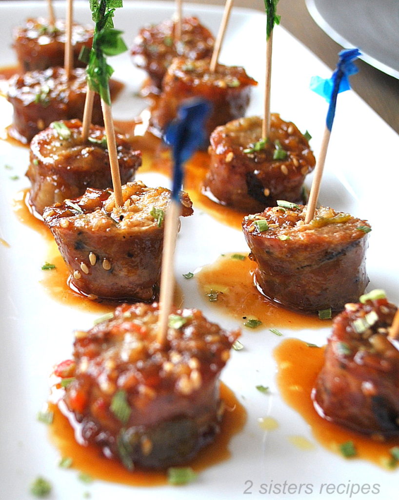 Little sausage bites  with cocktail toothpicks in each one dipped with sweet & sour sauce .