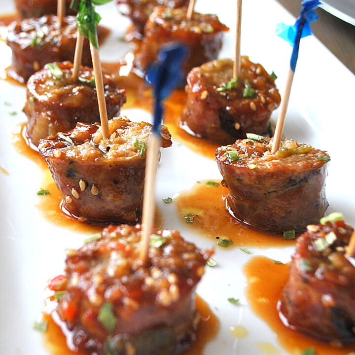 Sausage Bites with toothpicks inserted into each one served on a white platter.