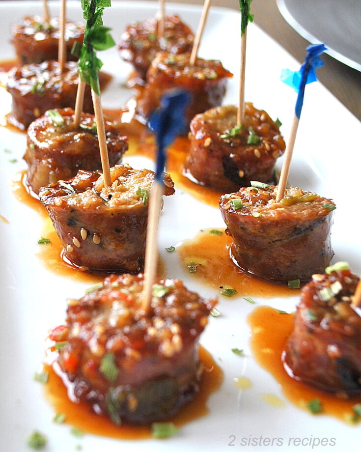 Sausage Bites with toothpicks inserted into each one served on a white platter.