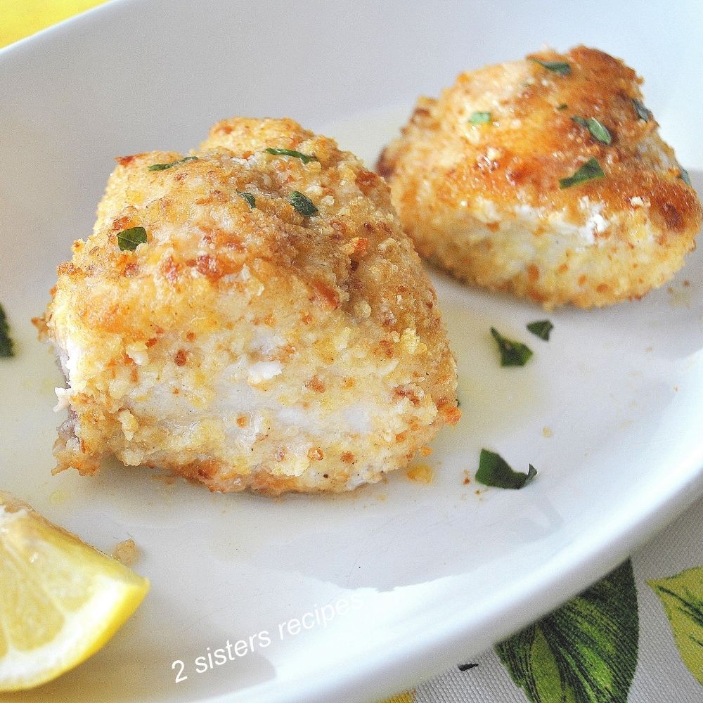 Two pieces of baked fish coated with bread crumbs, served on a white plate.