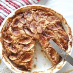 A white pie dish with a baked cinnamon apple coffee cake.
