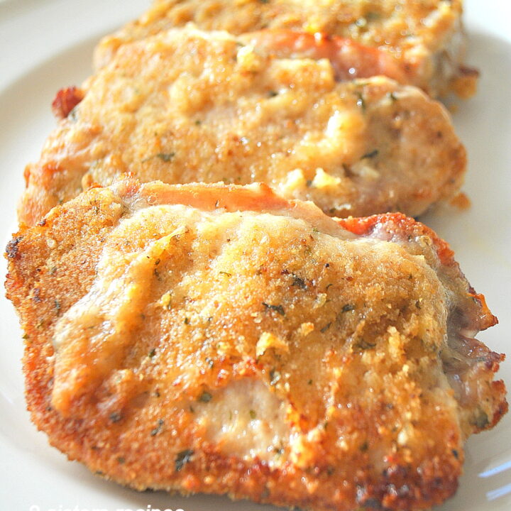 Three baked pork chops stuffed with prosciutto and cheese, served on a white plate.