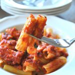 A forkful of rigatoni pasta with tomato sauce on top.