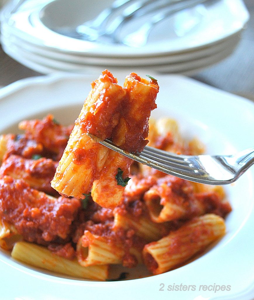 A forkful of rigatoni pasta with tomato sauce on top.