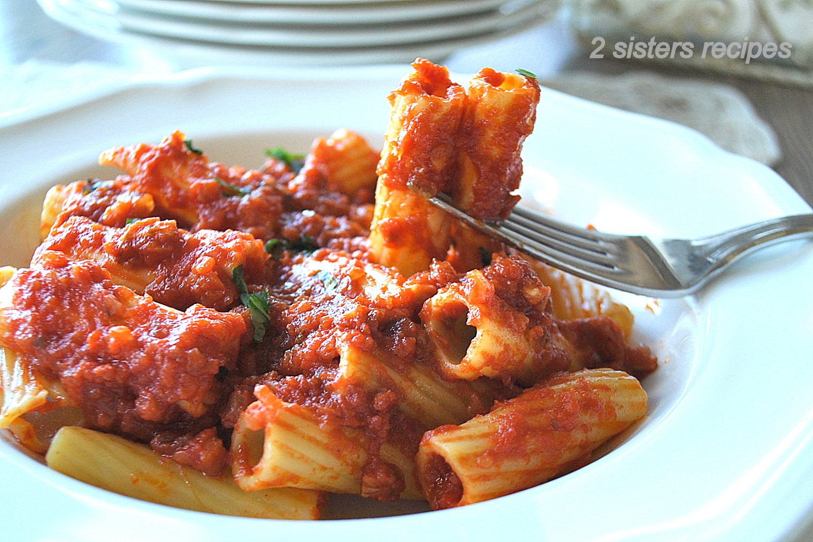 A forkful of rigatoni pasta with tomato sauce on top.