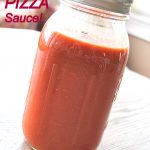 A glass jar filled with tomato pizza sauce.