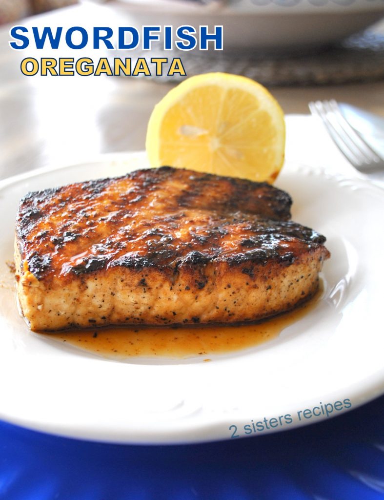 A grilled swordfish steak served on a white plate with a lemon on the side.