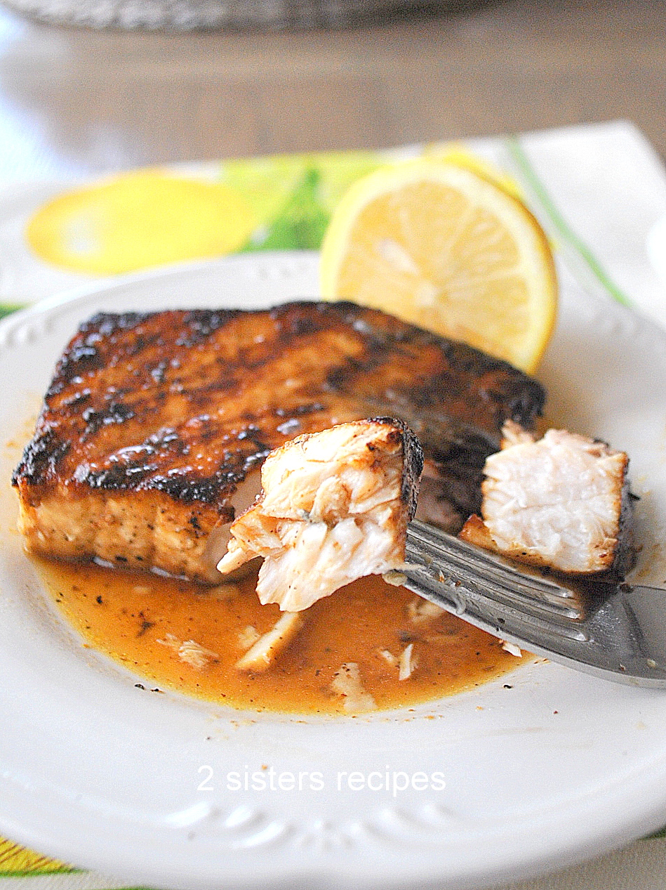 A forkful of grilled swordfish served on a white plate.