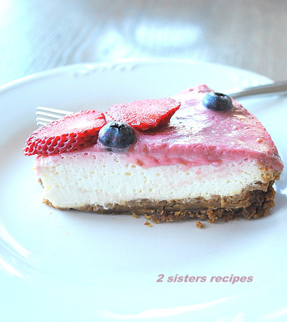 One wedge of the cheesecake on a white plate.  by 2sistersrecipes.com