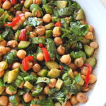 A white bowl filled with chickpeas, chopped cucumbers, peppers and basil salad.