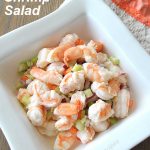 A white serving bowl filled with shrimp salad.