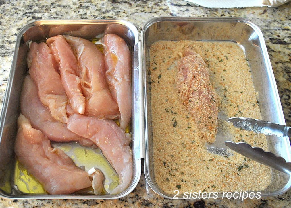 Chicken tenderloins in a breading pan with bread crumbs.  by 2sistersrecipes.com