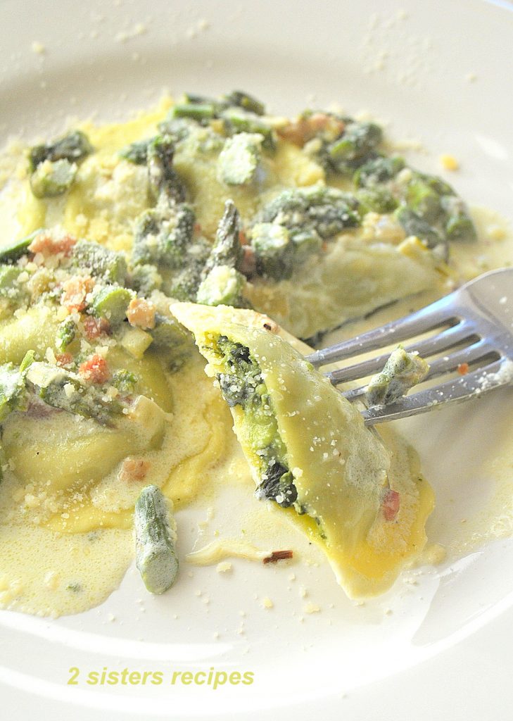 A Forkful of ravioli on a white plate with asparagus sauce,