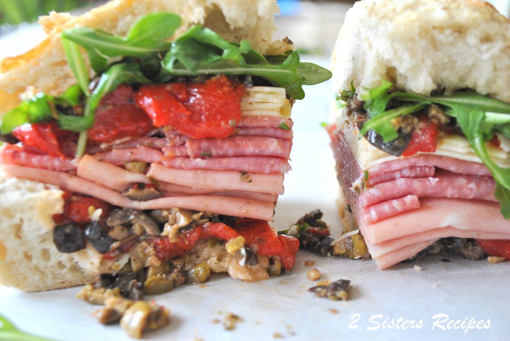 thick sandwich filled with deli meats, cheeses, chopped olives , roasted peppers, and arugula.