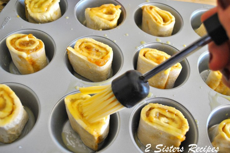 Brushing egg wash on each roll, in a muffin pan. by 2sistersrecipes.com 