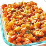 A glass casserole dish filled with baked chunks of butternut squash and sweet potatoes.