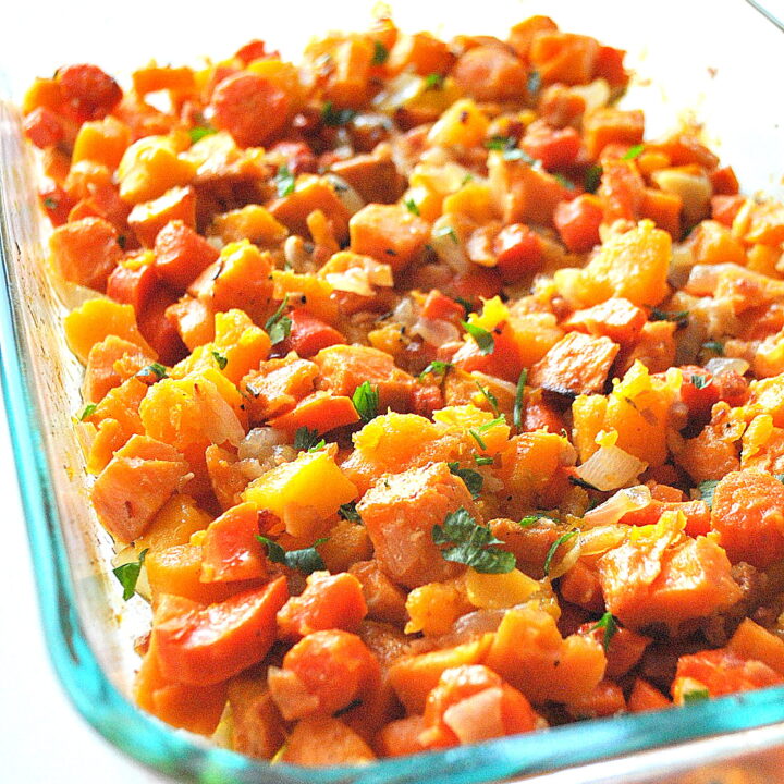 A glass casserole dish filled with baked chunks of butternut squash and sweet potatoes.