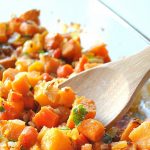 A glass baking dish filled with a casserole of chopped butternut squash, and sweet potatoes.