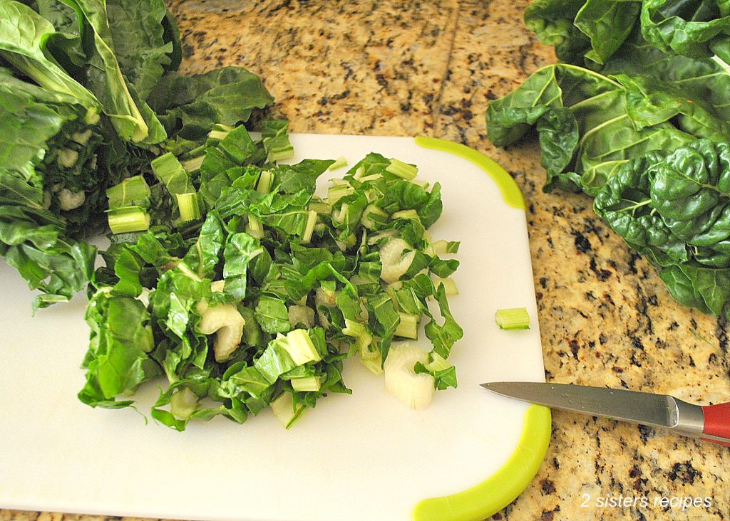  Chopped Swiss chard on a white cutting board. by 2sistersecipes.com