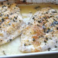 Two pieces of baked white fish in a ceramic baking dish.