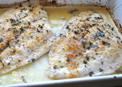 Two pieces of baked white fish in a ceramic baking dish.