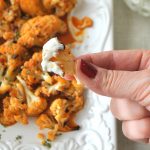 Someone holding a cauliflower wing with Homemade Buffalo Sauce.