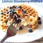 A forkful of waffles with fresh blueberries.