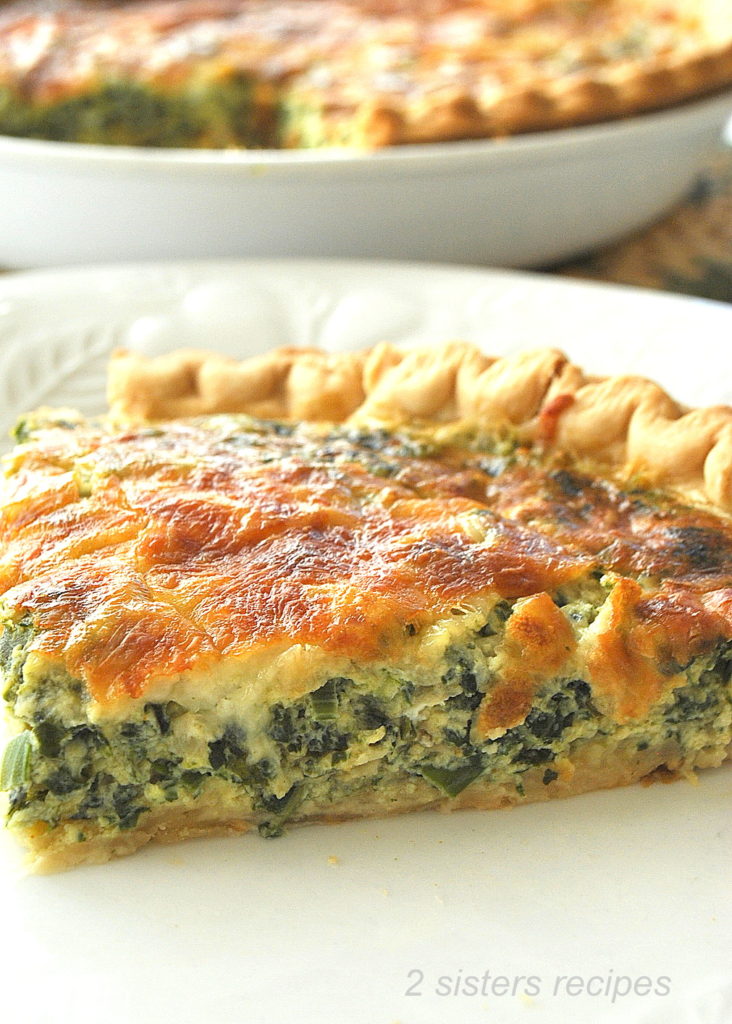 A slice of spinach quiche on a white plate.