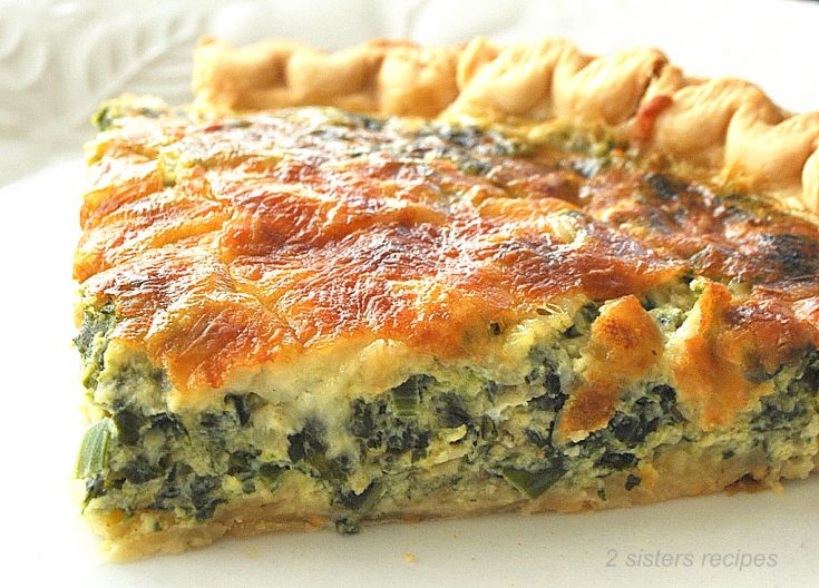 A slice of a baked golden pie loaded with a spinach and cheese mixture.
