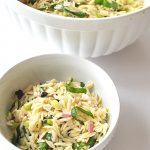 A white bowl filled with orzo salad.